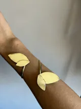 Brazalete abierto de metal dorado con apliques de hojas.