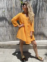 Vestido camisero corto color verde lima, con cuello en V, mangas 3/4 y cierre frontal con botones.