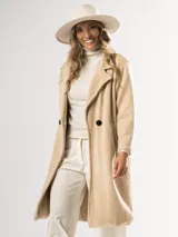 Tapado clásico color beige, con solapas de muesca, doble botonadura y bolsillos laterales.