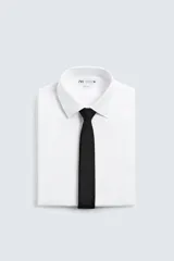 Corbata estrecha de seda negra con textura jacquard de pequeños puntos en relieve.