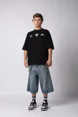 Remera de corte oversize color negro, confeccionada en algodón premium. Presenta un diseño gráfico minimalista estampado en el frente con tipografía y logotipos en color crema.