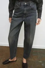 Jeans de tiro alto con corte barrel y diseño tapered, confeccionados en denim con efecto lavado y detalle de raya planchada. Presentan cintura con trabillas, cierre frontal con cremallera y botón, y bolsillos funcionales en delantero y espalda.