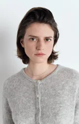 Cardigan de punto gris con cuello redondo, cierre frontal de botones y mangas largas. Presenta una textura esponjosa y un corte holgado.