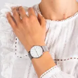 Reloj de pulsera Skagen modelo Signatur con caja de acero inoxidable plateado de 38mm y malla metálica tipo milanesa. Presenta una esfera blanca minimalista con marcadores lineales y puntos, y mecanismo de cuarzo de dos agujas.