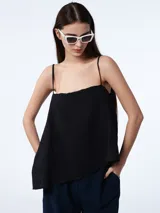 Top negro con escote recto y breteles finos, de corte holgado y asimétrico en el ruedo.