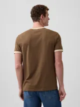 Remera de manga corta color rojo con detalles en azul marino en el cuello y los puños, cuenta con un bolsillo aplicado en el pecho.