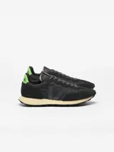 Championes Veja modelo Rio Branco II Lite, color negro con detalles en verde fluo en el talón y suela en tono tostado. Confeccionados con paneles de gamuza sintética y tejido técnico, presentan el logotipo "V" en el lateral.