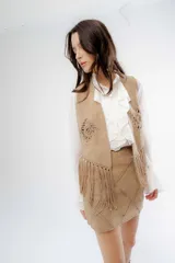 Pollera corta de simil gamuza color beige, con diseño de pespuntes decorativos en forma de rombos y cierre posterior.