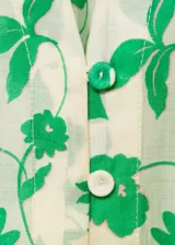 Blusa de tejido semitransparente con estampado floral en tonos verdes sobre fondo claro. Presenta escote en pico, cierre frontal con botones y mangas largas abullonadas con puños abotonados.