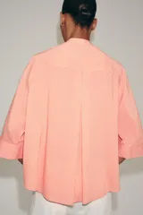 Camisa ZARA Woman Collection confeccionada en hilatura con viscosa, con diseño de rayas finas y color salmón. Presenta cuello perkins, mangas por debajo del codo, bajo asimétrico y cierre frontal cruzado con botones.