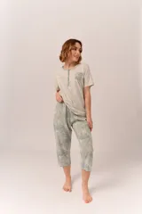 Conjunto de pijama de algodón color champagne, compuesto por una remera de manga corta con cuello henley y bolsillo en el pecho, y un pantalón capri a rayas horizontales celestes y blancas.