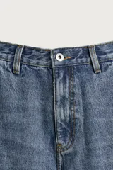 Jeans relaxed fit de tiro medio y pernera recta confeccionados en denim de algodón rígido, con diseño de carpintero que incluye bolsillos superpuestos y roturas localizadas en el frente.