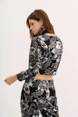 Saco corto de terciopelo negro con estampado floral plateado, cuello cuadrado, mangas largas y aberturas en la zona del abdomen.