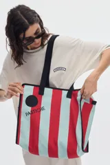 Cartera tote bag con diseño de rayas verticales en negro y blanco, asas de hombro y ribetes en color celeste. Cuenta con cierre superior y estampa con el nombre de la marca.