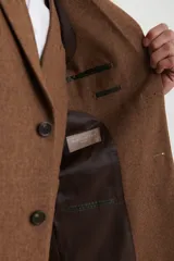 Saco de vestir marrón de corte clásico, con solapas de muesca, cierre de dos botones, bolsillo en el pecho y bolsillos laterales con solapa.