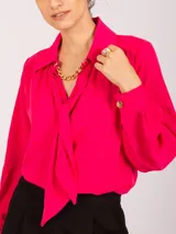 Blusa negra de manga larga con cuello camisero y lazo frontal. Presenta frunces en los hombros y puños ajustados con elástico.