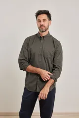Camisa de algodón con elastano, color verde militar oscuro, de manga larga y cuello button-down. Presenta un bolsillo de parche en el pecho izquierdo.