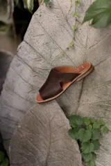 Bolso tipo tote de cuero marrón oscuro, con diseño minimalista, costuras reforzadas con remaches metálicos y correas largas para llevar al hombro.