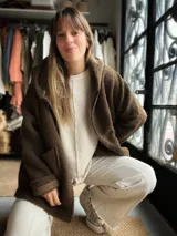 Campera estilo sherpa color verde militar, con capucha y diseño oversize. Presenta un gran aplique geométrico en la espalda en tonos tostado, blanco y un círculo con estampado animal print.