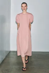 Vestido midi de cuello redondo y manga corta abullonada con terminación elástica. Presenta un diseño de corte evasé con cierre posterior de cremallera oculta.
