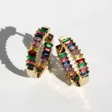 Par de aros tipo argolla dorados, cubiertos de cristales multicolores.