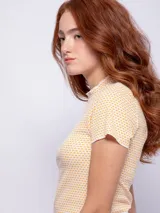Remera corta color amarillo con estampado de lunares blancos, cuello alto y mangas cortas.