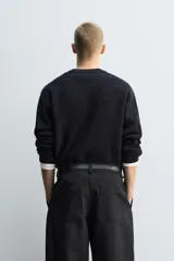 Jersey de punto con diseño boxy fit, cuello redondo y manga larga. Presenta una textura acanalada y acabados en rib en cuello, puños y ruedo.