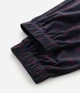 Pantalón de pijama tipo jogger para hombre, confeccionado en tejido plush suave y abrigado. Presenta un diseño estampado a cuadros, cintura elástica con cordón de ajuste y puños elásticos en los tobillos.
