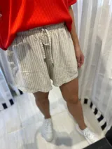 Short de lino color beige con rayas verticales negras y cintura elastizada con cordón ajustable.