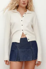 Short pollera de denim azul oscuro con diseño de pliegues frontales, cintura estándar y cierre lateral.