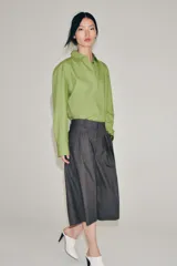 Camisa oversize de popelín de algodón color verde claro, con cuello solapa y manga larga. Cierre frontal con botones ocultos y bajo redondeado.
