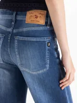 Jeans de denim azul con diseño clásico de cinco bolsillos, silueta semi oxford de tiro medio-alto, entallada en caderas y muslos con botamanga acampanada. Presenta lavado en azul medio con contrastes y desgastes focalizados.