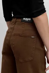 Pantalón de jean color marrón, de corte recto y tiro medio, con cierre de botón y cremallera, y bolsillos laterales.