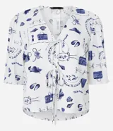 Blusa de mangas abullonadas cortas, confeccionada en Viscolino con 15% de Lino, con cuello v con lazo y estampa de accesorios de playa.