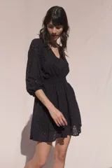 Vestido corto negro de broderie de algodón, con escote en V, mangas tres cuartos, cintura elastizada, falda corte A con volado y forro interior.