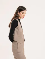 Chaleco de vestir gris oscuro con textura tipo tweed, escote en V y botones frontales. Corte levemente entallado y largo a la cintura.