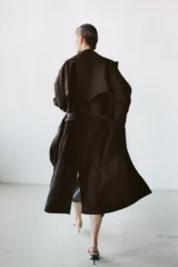 Trench fluido de corte recto confeccionado en lana, con cuello solapa, manga larga, bolsillos delanteros y cinturón ajustable del mismo tejido.