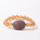 Pulsera elástica con cuentas redondas color ámbar y cuenta central ovalada color marrón.