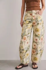 Jean de tiro alto con corte barrel y diseño estampado de flores en tonos beige, blanco, amarillo y verde.