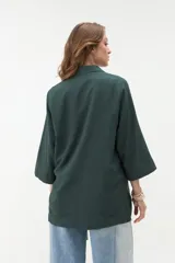 Blazer negro de corte recto y holgado, con doble botonadura frontal, solapas clásicas y mangas tres cuartos con costuras pespunteadas en contraste.