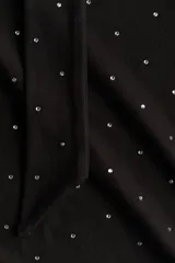 Remera de manga larga en punto elástico, color negro con estampado de lunares pequeños en color blanco. Presenta un diseño entallado con cuello drapeado y una tira lateral decorativa.