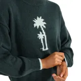 Buzo de punto color verde oscuro con diseño de palmeras tejido en color claro en el centro. Presenta cuello redondo, mangas largas con puños acanalados y detalle de borde en color contrastante en los puños y el ruedo.
