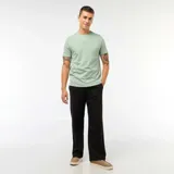 Pantalón tipo chino de corte ancho y tiro medio, confeccionado en tela de algodón con acabado liso y cierre frontal con botón y cremallera.