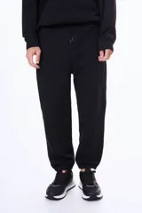 Pantalón deportivo de felpa color negro, con cintura elástica ajustable mediante cordón, puños elásticos en los tobillos y bolsillos laterales.