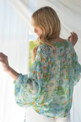 Blusa estampada en tonos de verde, celeste y amarillo, con sutiles hilos de lurex dorados. Cuello con lazo y abotonadura, y corte en el pecho con fruncido.