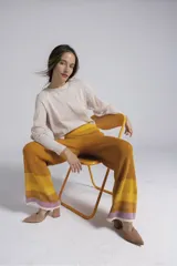 Pantalon de tejido de punto con diseño de rayas horizontales en degradado de tonos mostaza, naranja y lila en el ruedo. Presenta corte recto, tiro alto y cintura elástica ancha.