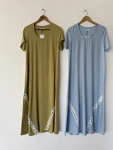 Vestido largo celeste con mangas cortas, escote redondo y detalles de pasamanería geométrica en los laterales de la falda.