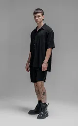 Camisa de manga corta con cuello solapa, confeccionada en lino. Presenta un corte oversize y cierre frontal con botones.