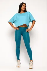 Remera corta de manga corta color celeste, con escote amplio en la espalda que se anuda en la parte inferior, dejando ver un top deportivo amarillo con tiras cruzadas.