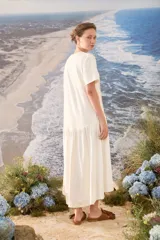 Vestido midi color crudo de manga corta, con corte en la cintura y falda holgada con volados y detalle de pequeño bordado de hongo en el pecho.